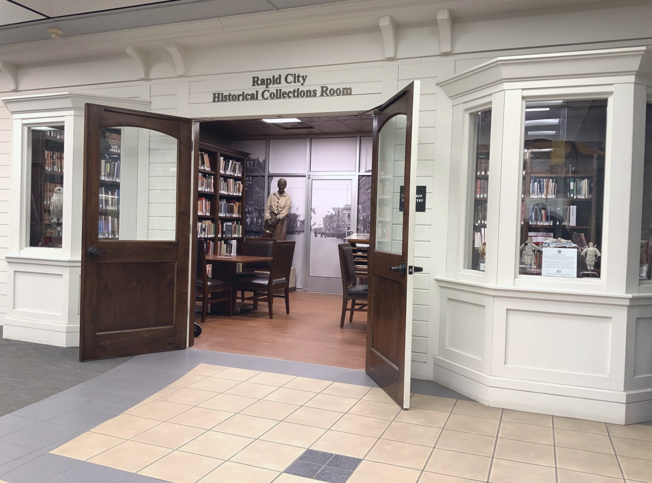 Entrance to the Rapid City Historical Collections Room with open wooden double doors, white paneled walls, and display cases with artifacts.