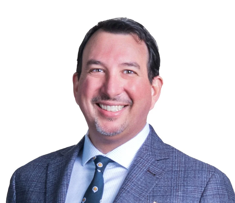 A smiling man wearing a suit, white shirt, and patterned tie, against a plain white background.