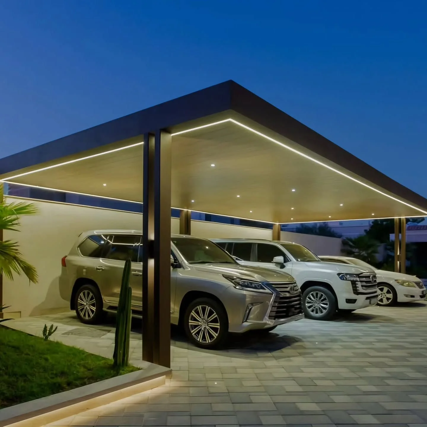Modern carport with four parked SUVs, illuminated with LED lighting, under a flat roof during evening.