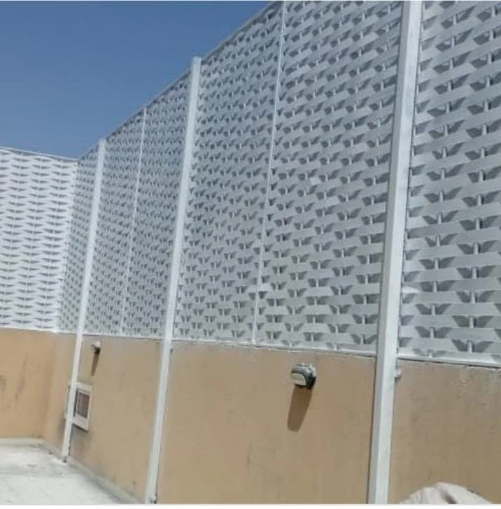 Exterior view of a tall privacy fence with a lattice upper section and tan lower section, with utility boxes attached, under a clear blue sky.