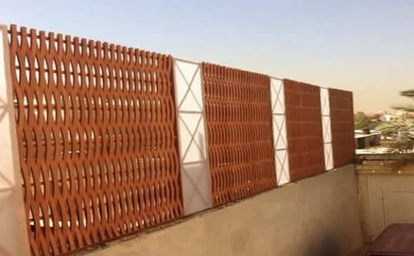 A brown decorative privacy fence installed on a rooftop, with a cityscape in the background during sunset.