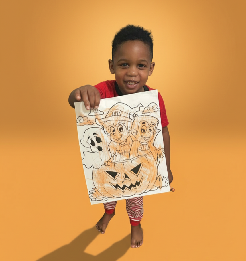 A smiling young boy holding a Halloween-themed drawing with a smiling pumpkin, witches, and a ghost, standing against a solid yellow background.