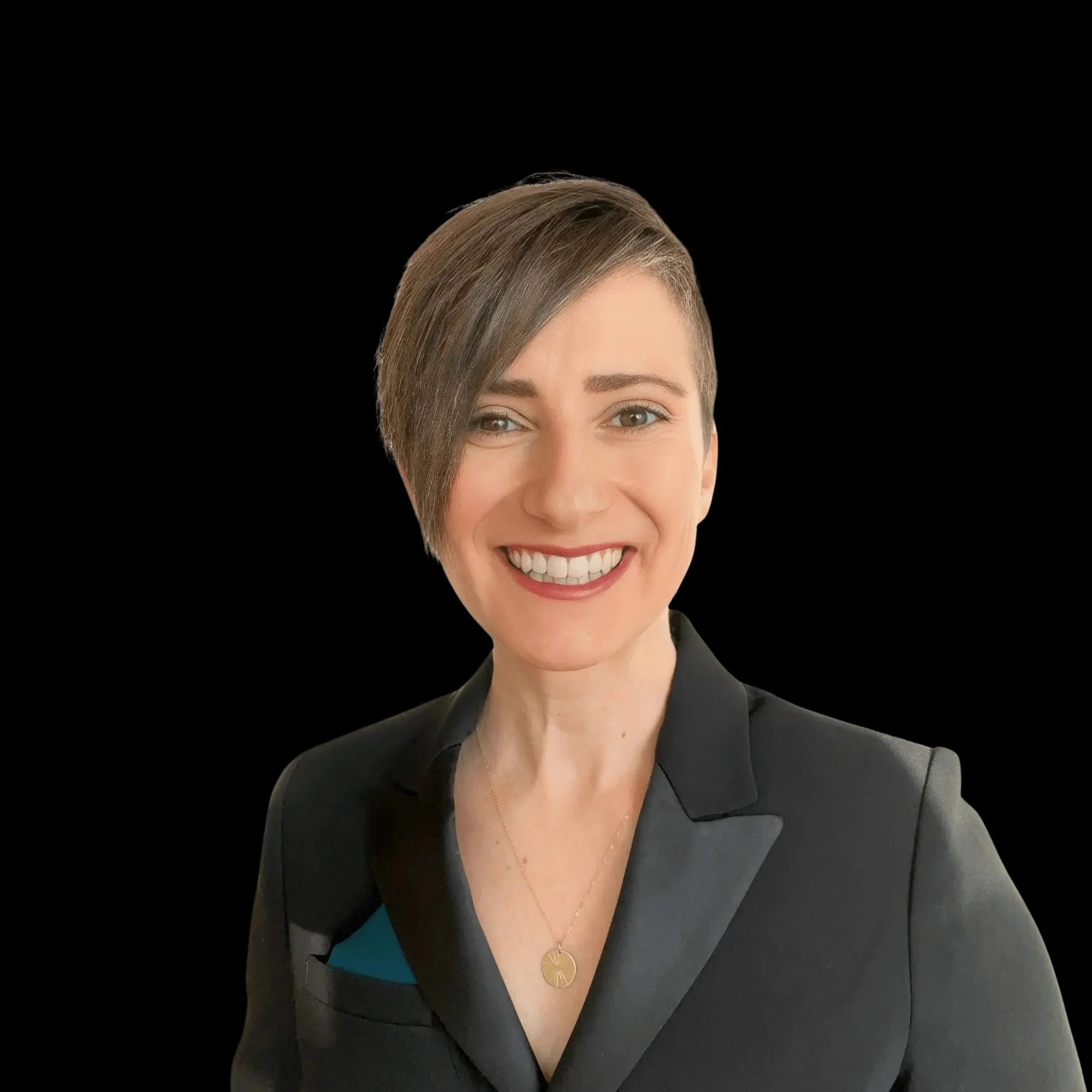Portrait of a woman with short brown hair, smiling, wearing a black blazer and a necklace, against a black background.