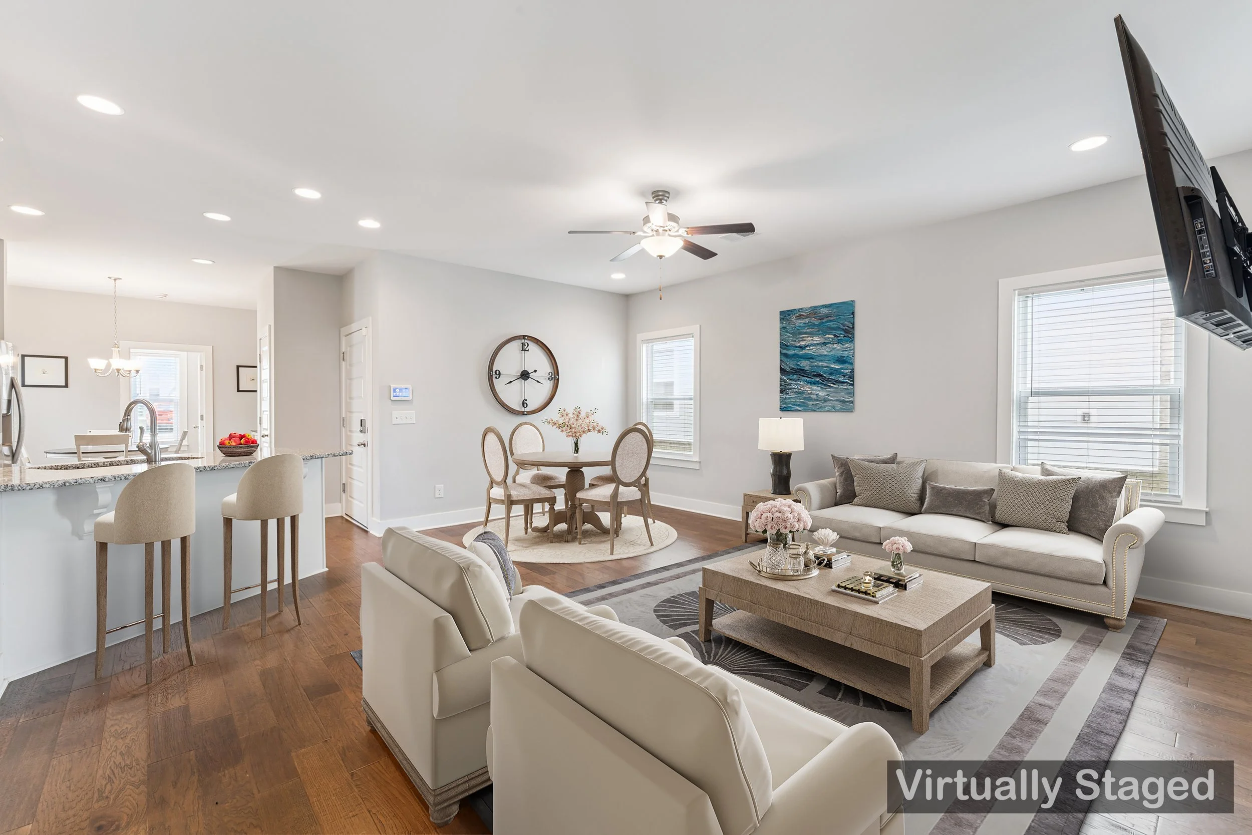 Living room with white couch, armchair, coffee table, wall art, TV, ceiling fan, and windows.