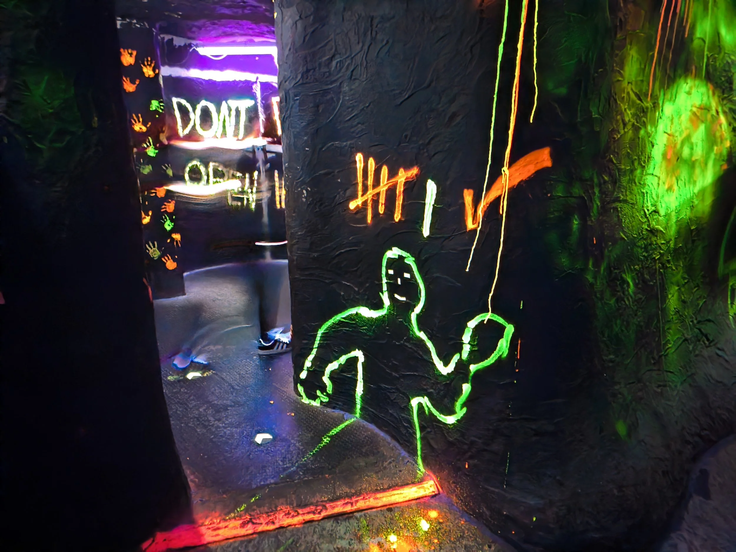 Neonlichter im Dunkeln, ein menschliches Silhouettenbild und das Wort 'DON'T' in leuchtenden Buchstaben.