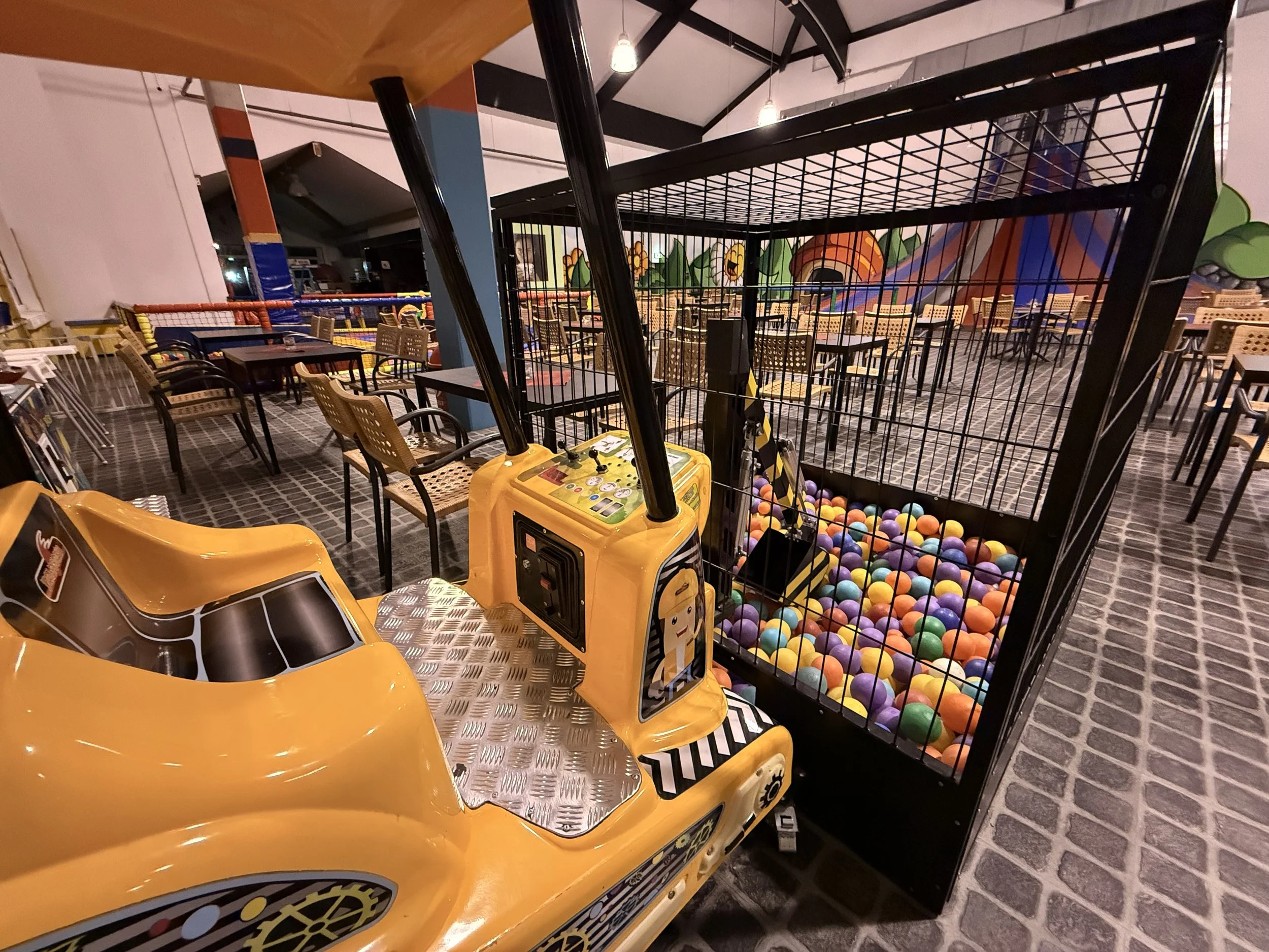 Kinder-Spielzeug mit kleiner gelber Spielzeugauto und Ballkiste voller bunter Bälle in einem Indoor-Spielplatz.