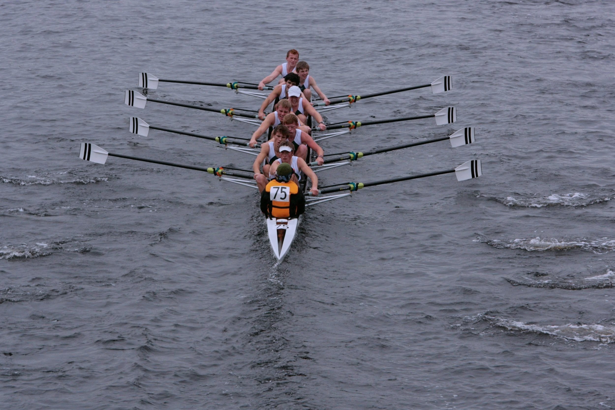A team of rowers in a boat on the water during a race, with all team members working together to paddle.
