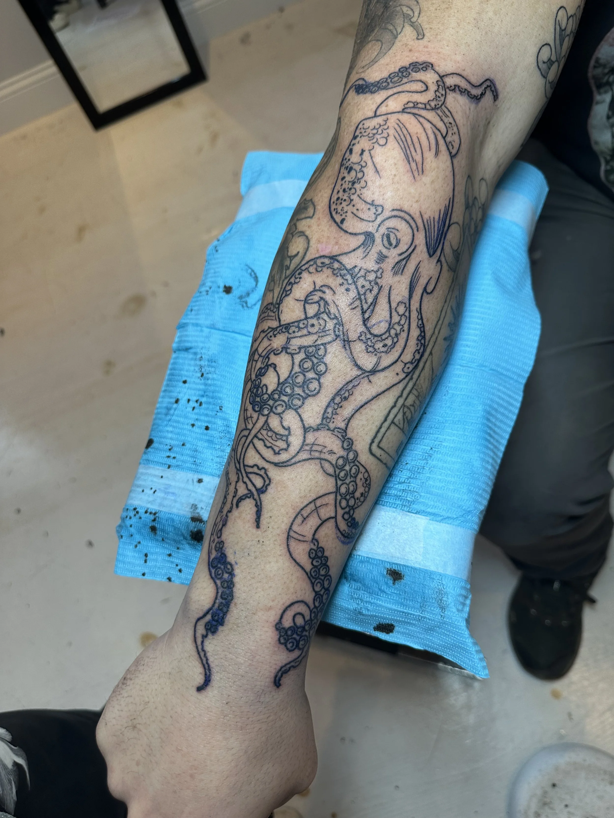 Outline of a tattoo of an octopus on a person's forearm.