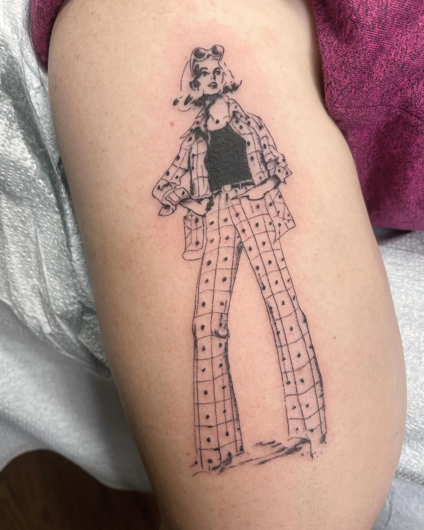 Tattoo sketch of a woman wearing plaid pants, a matching plaid jacket, and a black top, with sunglasses on her head, standing with hands in her pockets.