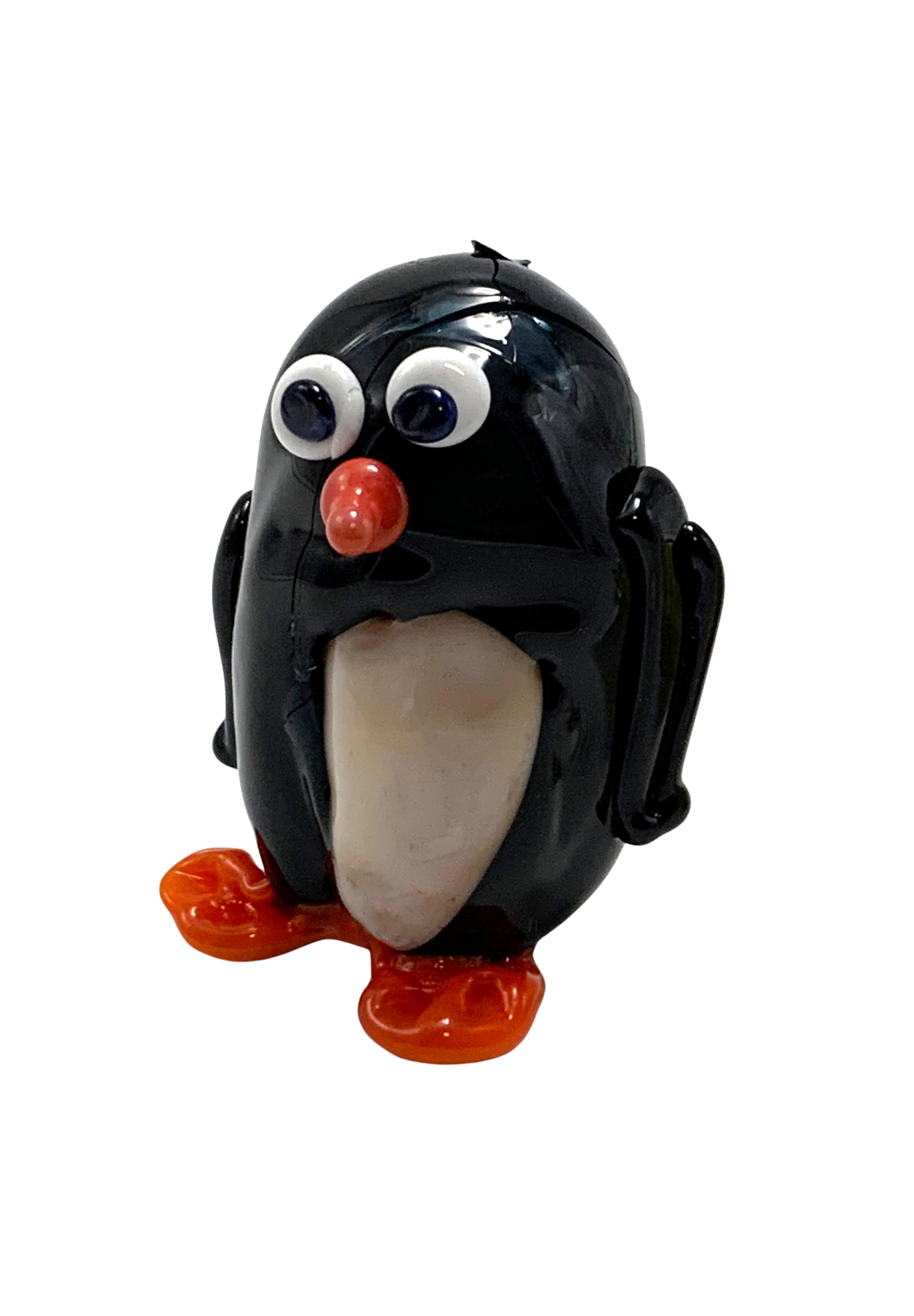 A small toy penguin with googly eyes, a red nose, and orange feet.