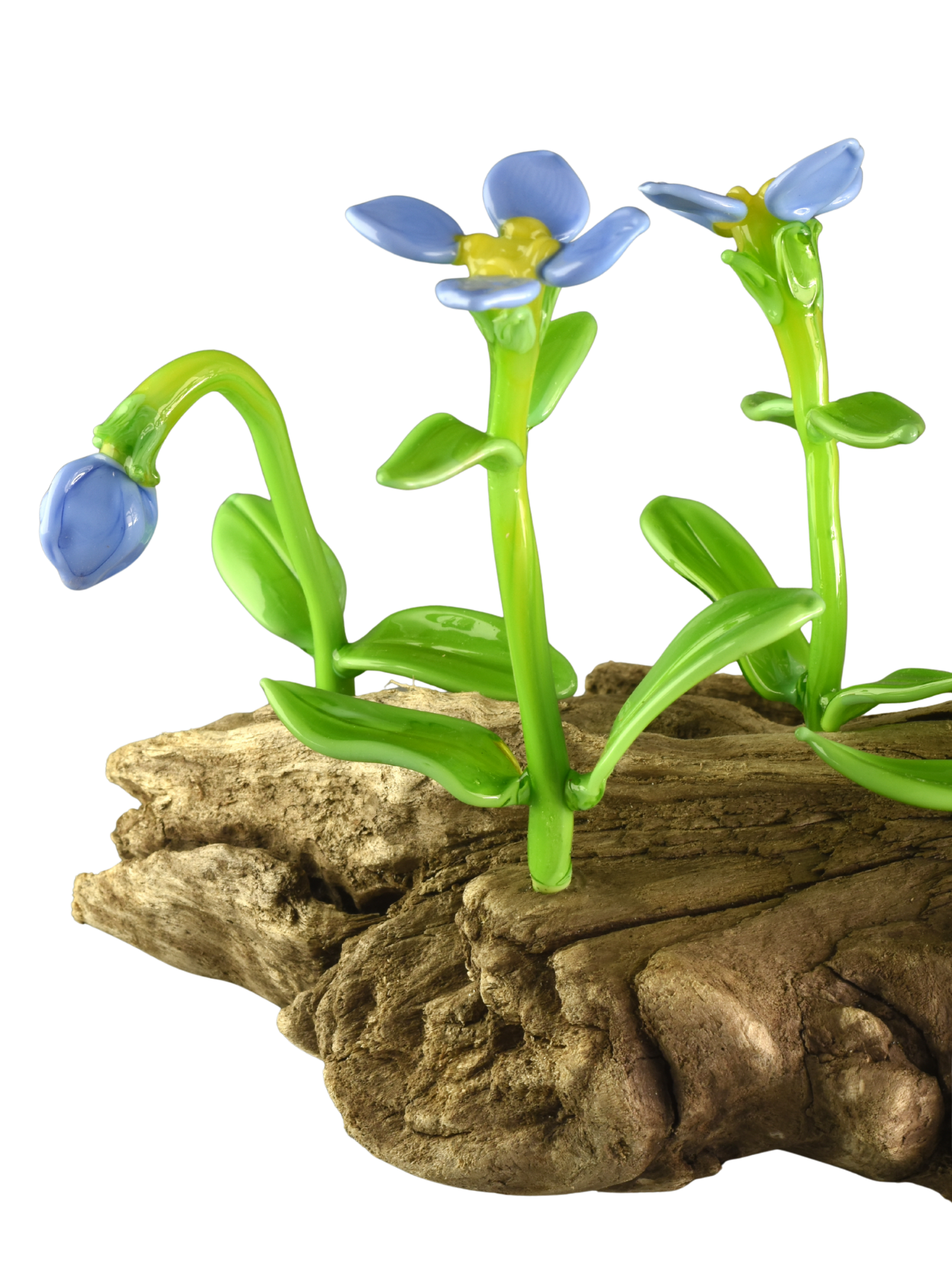 Colorful glass sculpture of blue and yellow flowers with green stems, set on a large piece of irregularly shaped wood.