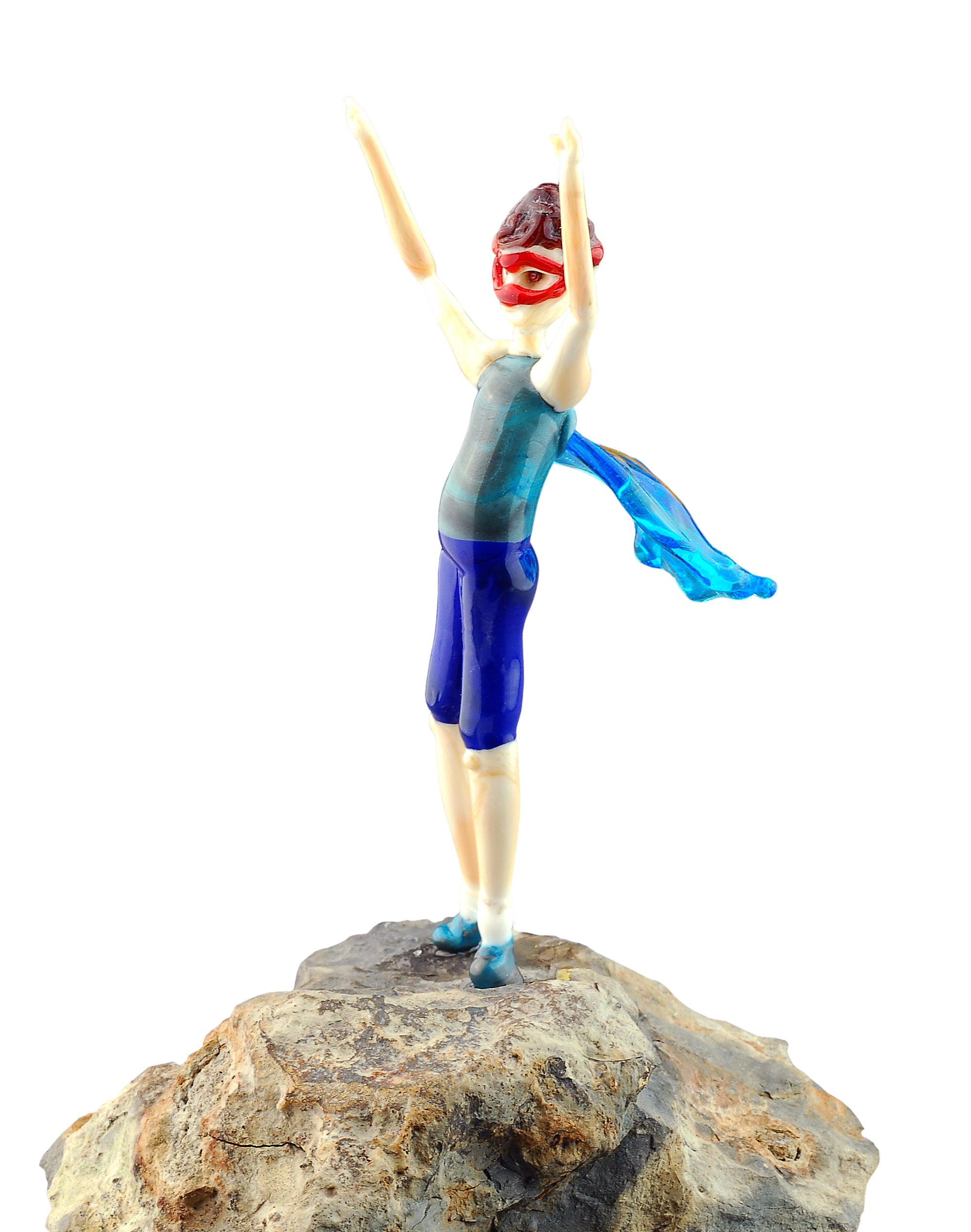 A sculpture of a woman with arms raised, wearing a blue dress, on a large rock, with a background showing a red, yellow, and green pattern.