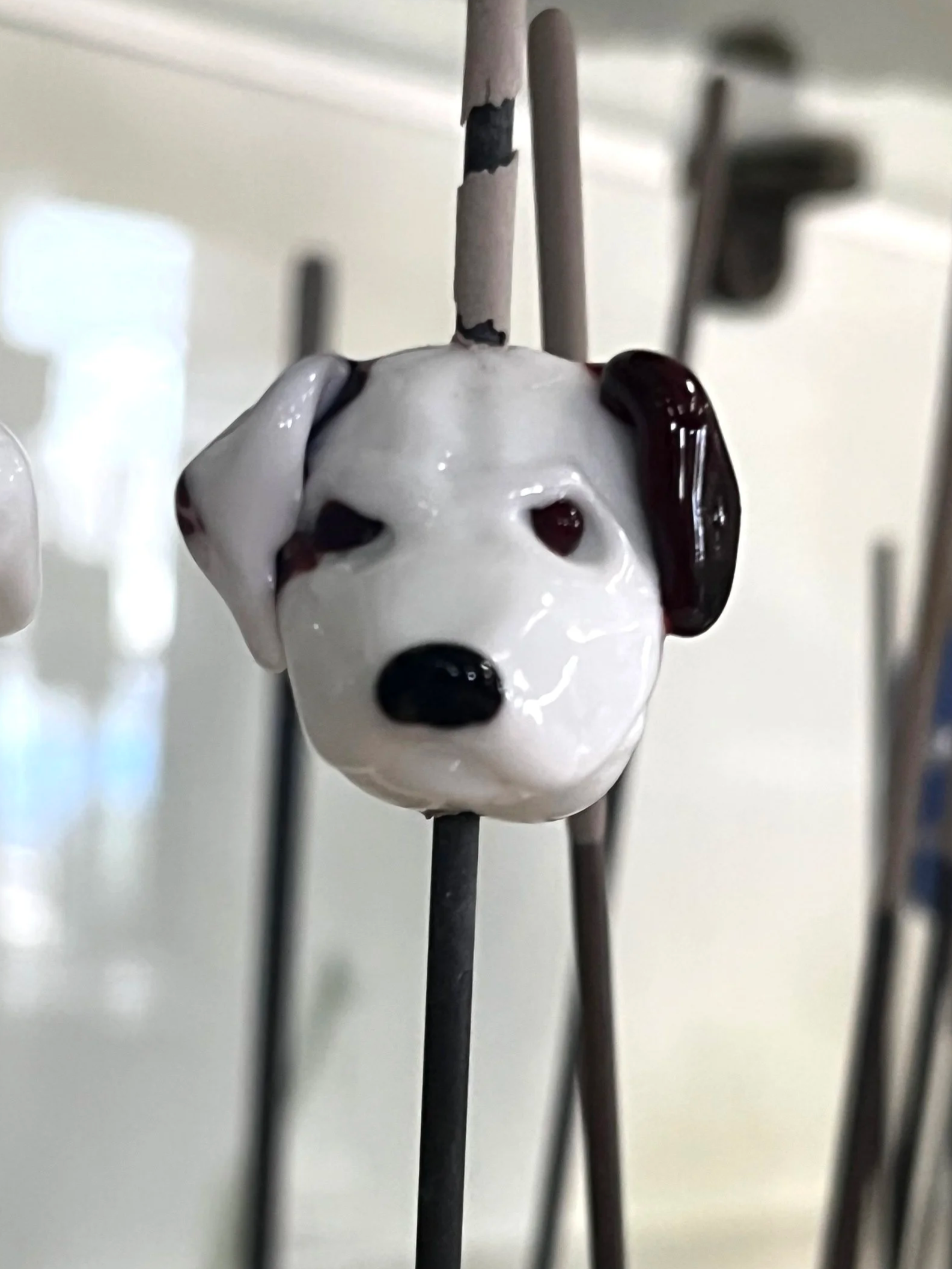 Close-up of a ceramic dog figurine with black and white spots hanging on a metal chain.