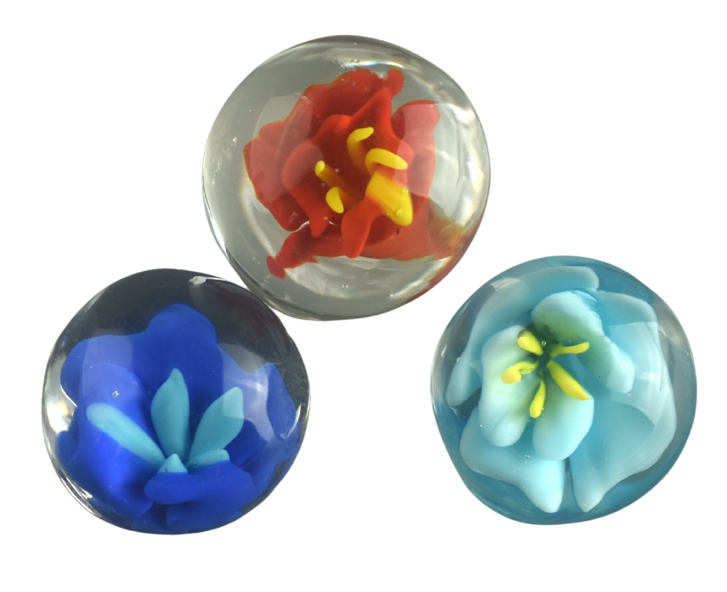 Three glass marbles with floral designs inside. The top marble has a red and yellow flower, the bottom left marble has a blue flower, and the bottom right marble has a white flower with yellow accents.
