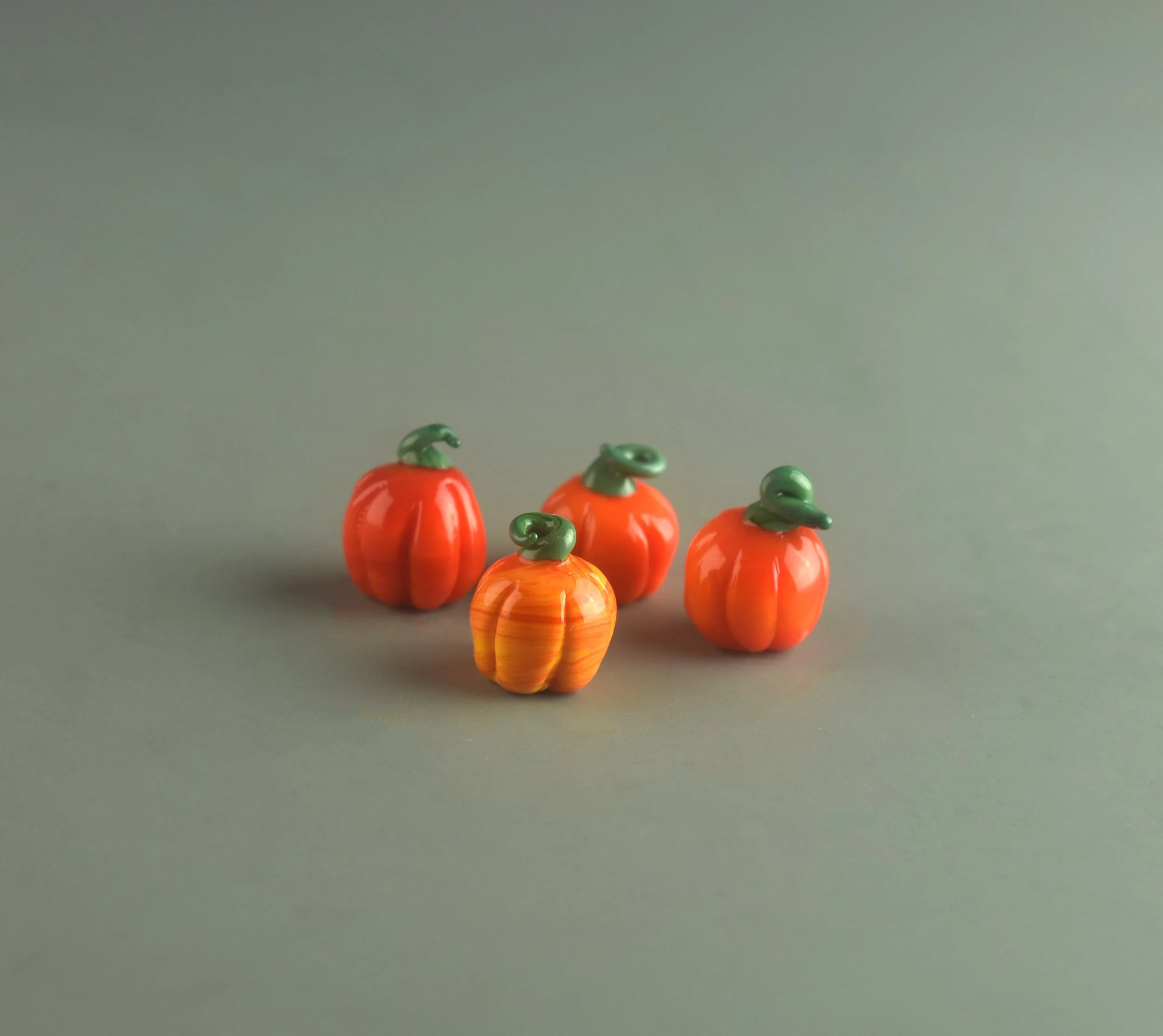 Several orange push pins with green toppers arranged on a gray surface, with a gray background.