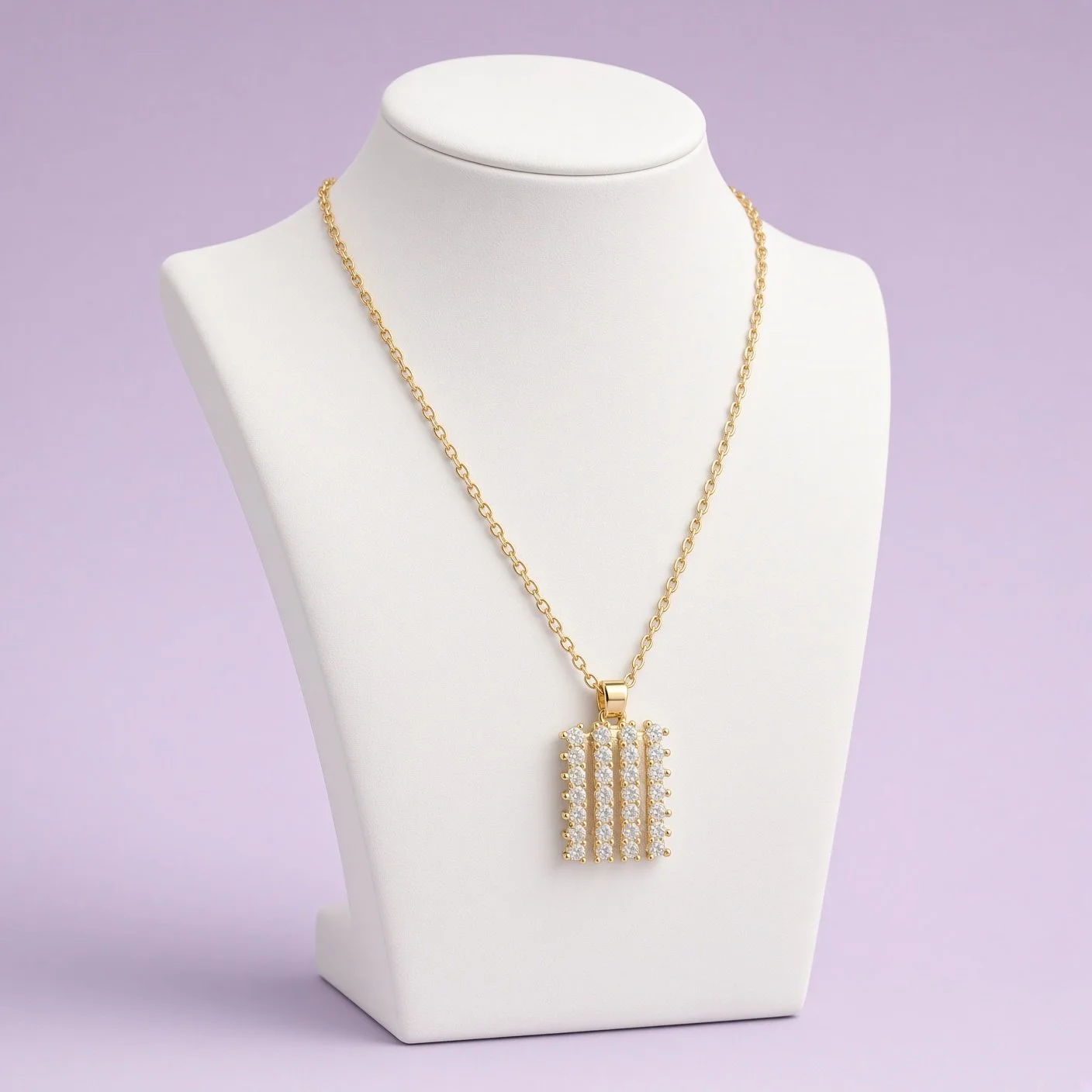 Gold rectangular bar pendant necklace with vertical stone rows on white bust against lilac