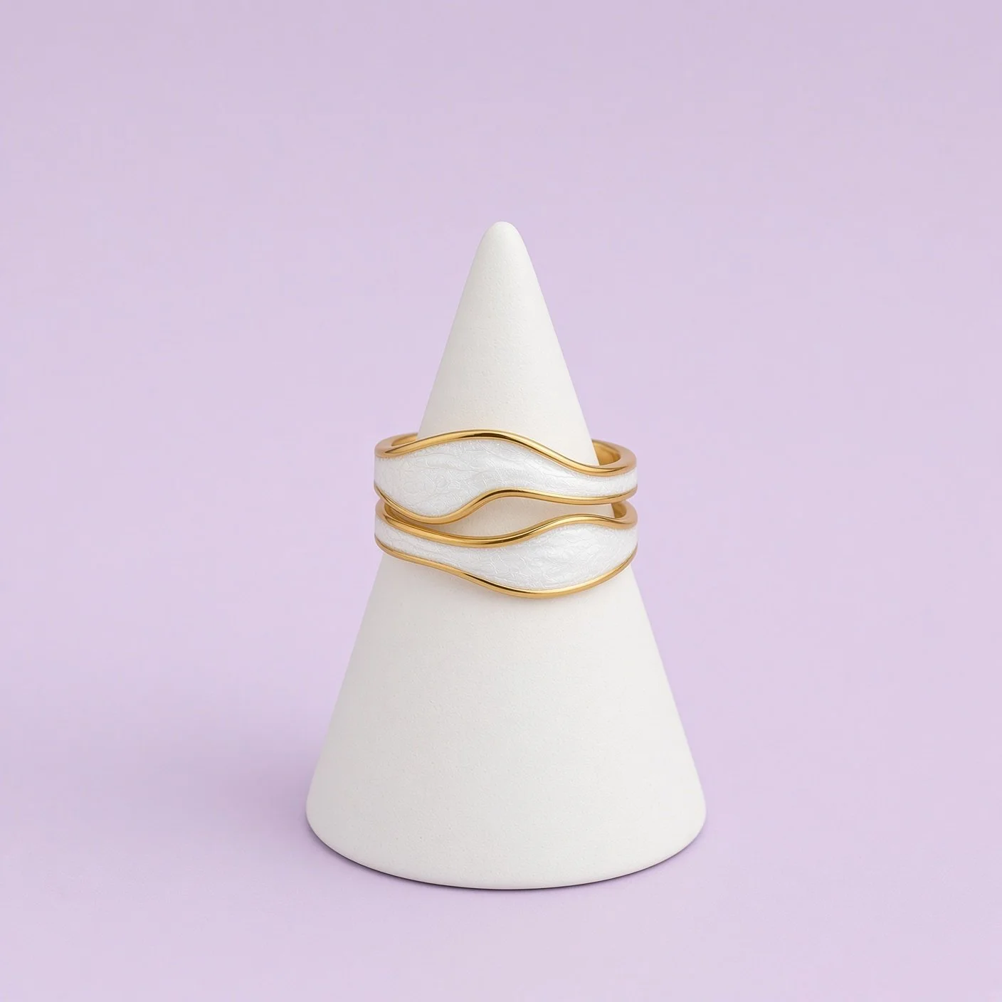 Gold and white enamel wave ring from Christmas Box Four on white cone stand, lilac background