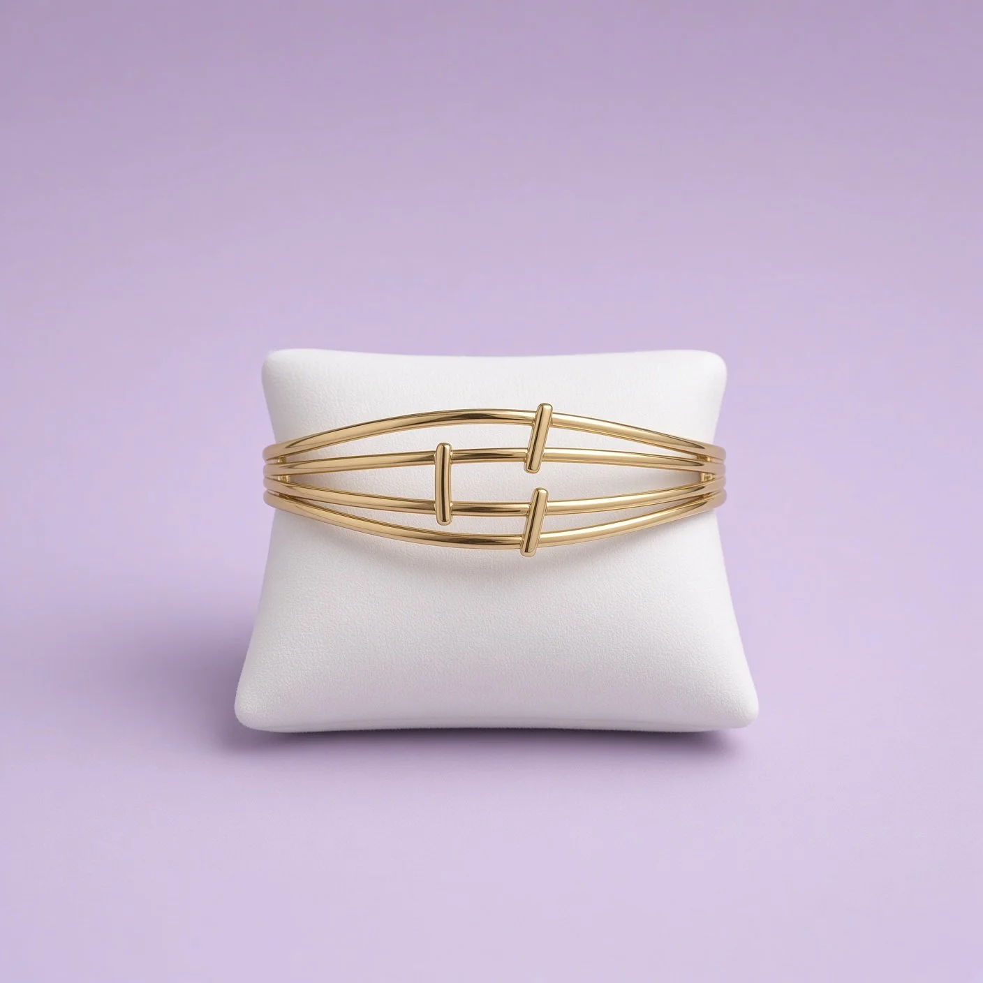 Gold multi-strand wire bangle from Laroc Jewel Christmas Box Five on white pillow stand, lilac background