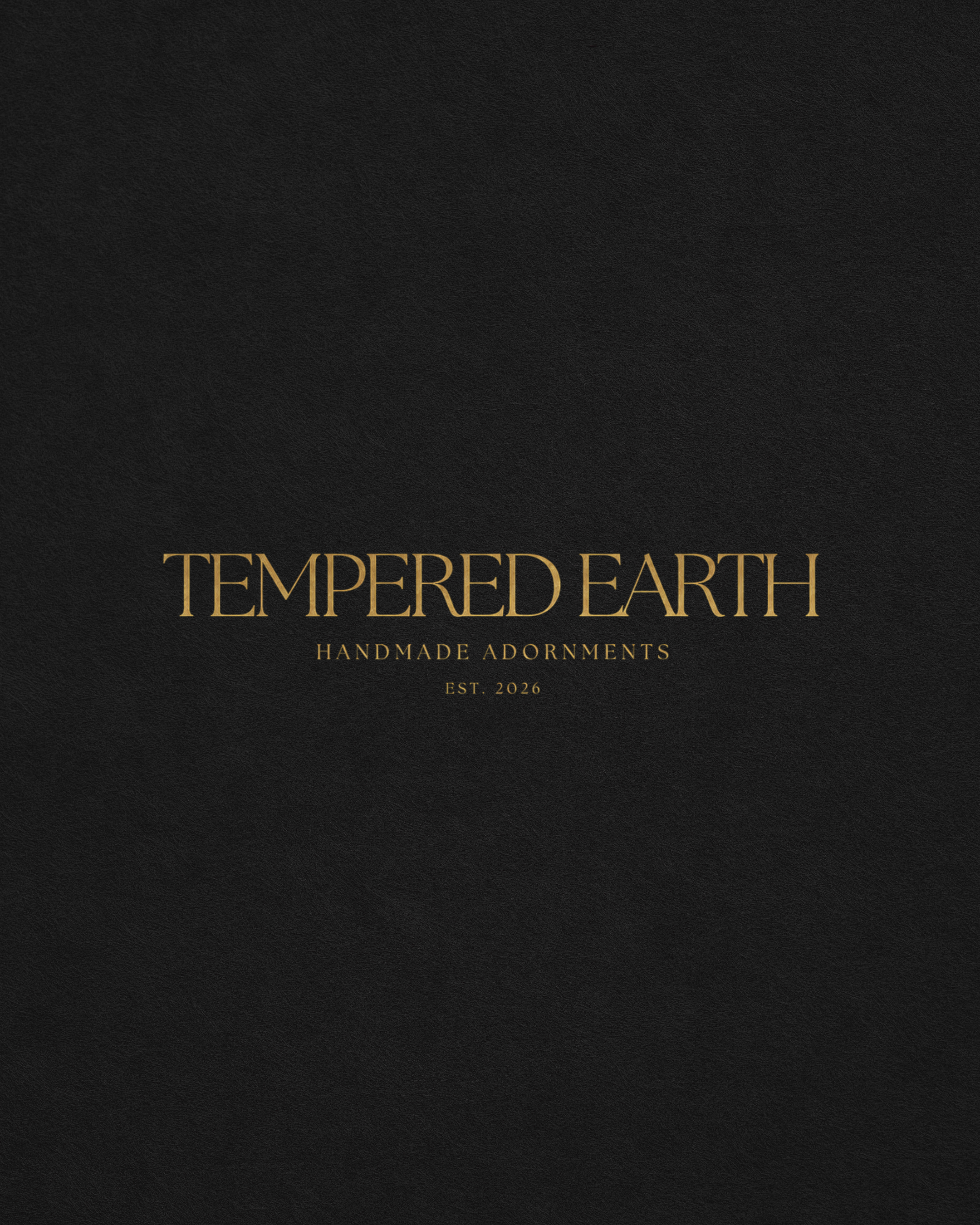 Black textured background with gold text that says, "TEMPERED EARTH HANDMADE ADORNMENTS EST. 2026."
