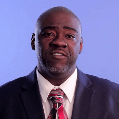An African American man in a suit and tie making a confused or concerned facial expression against a blue background.