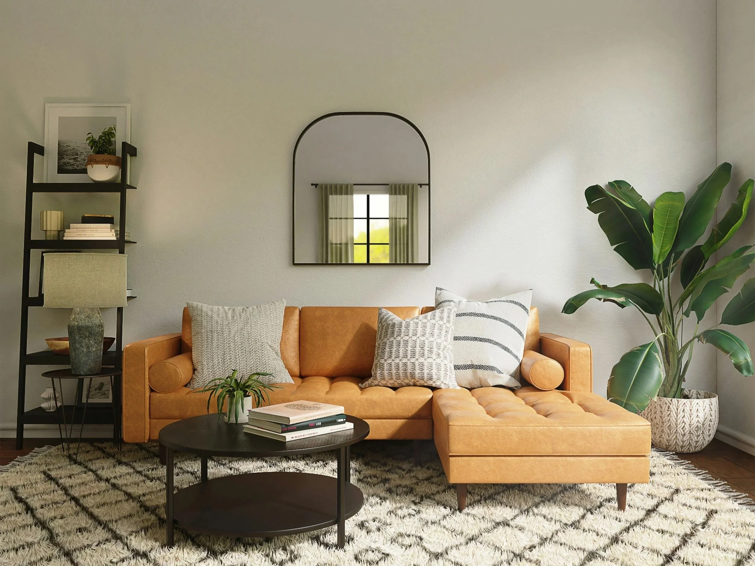 Living room with a tan leather sectional sofa, decorative pillows, a black coffee table with books and a plant, a black bookshelf with decor, a tall green plant in a woven pot, a mirror on the wall, and a window with green curtains.
