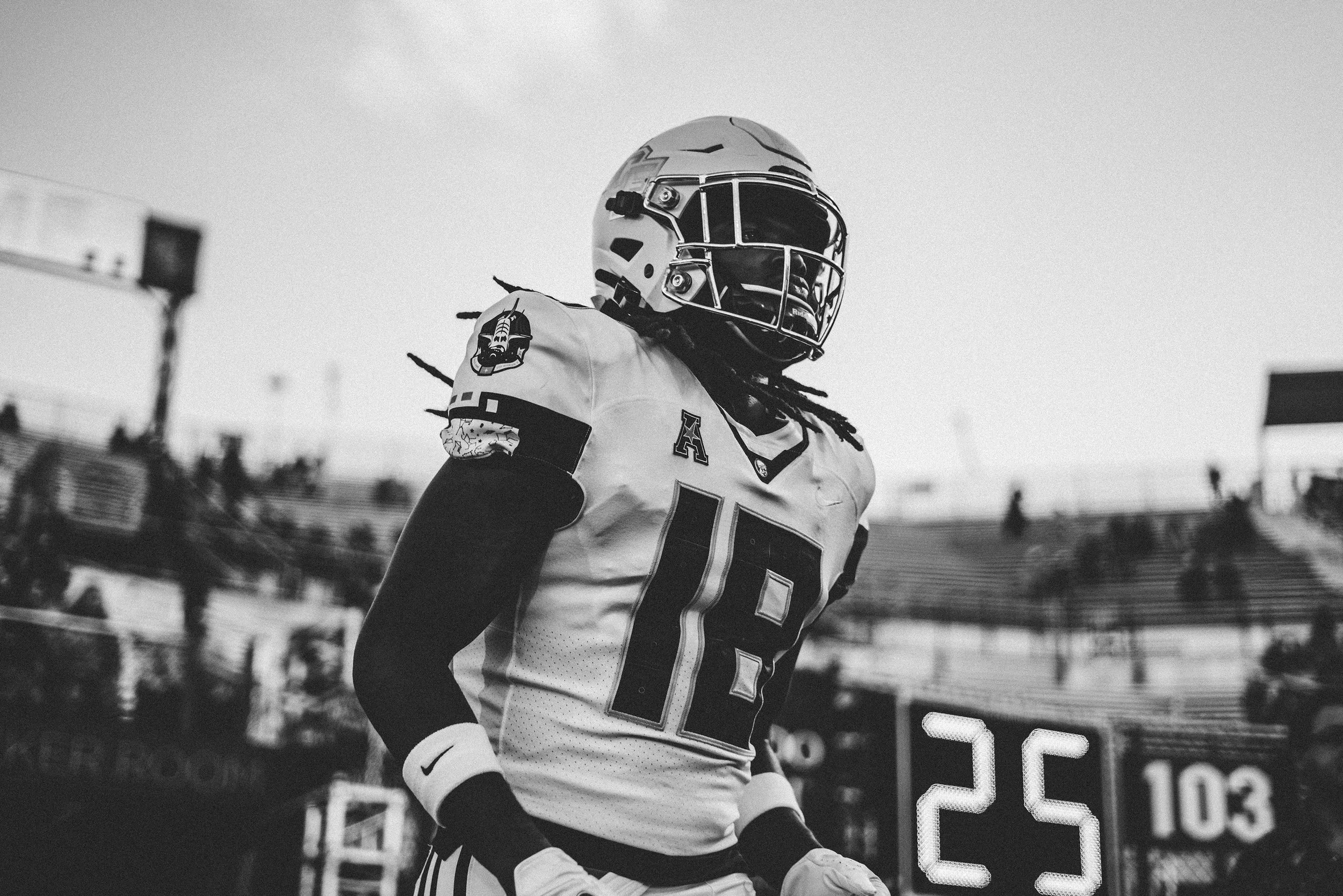 A football player wearing jersey number 18 with a helmet, standing on the field with a scoreboard showing 25 seconds remaining in the game.