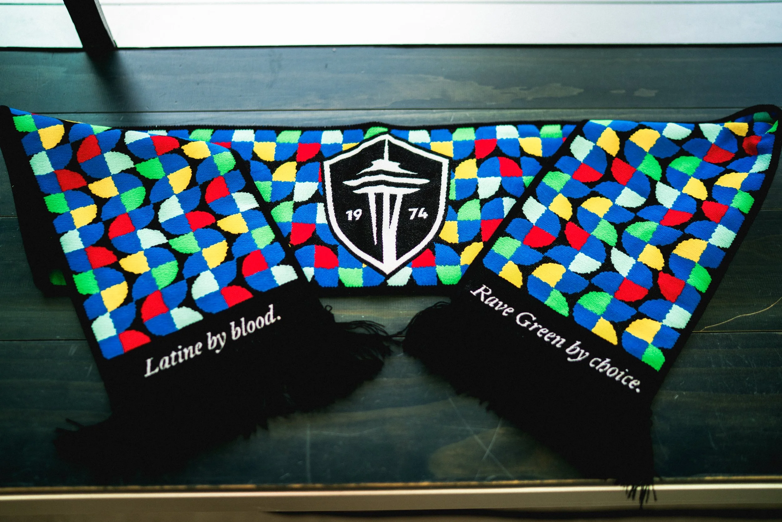 Colorful Seattle Seahawks scarf with team logo in the center, one side reading "Latin by blood." and the other side reading "Rave Green by choice."