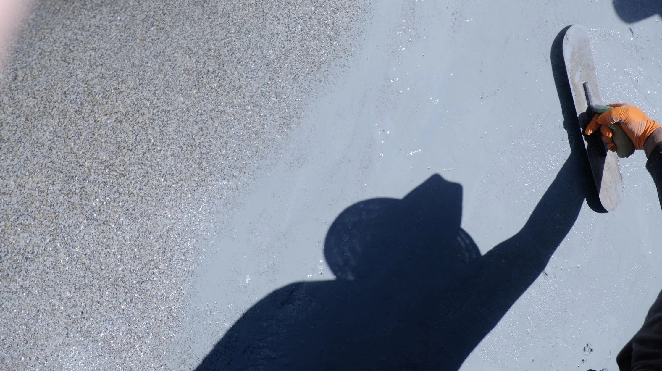 Pool plasterer using trowel to apply aggregate finish during swimming pool resurfacing by NorCal Pools Inc in Northern California