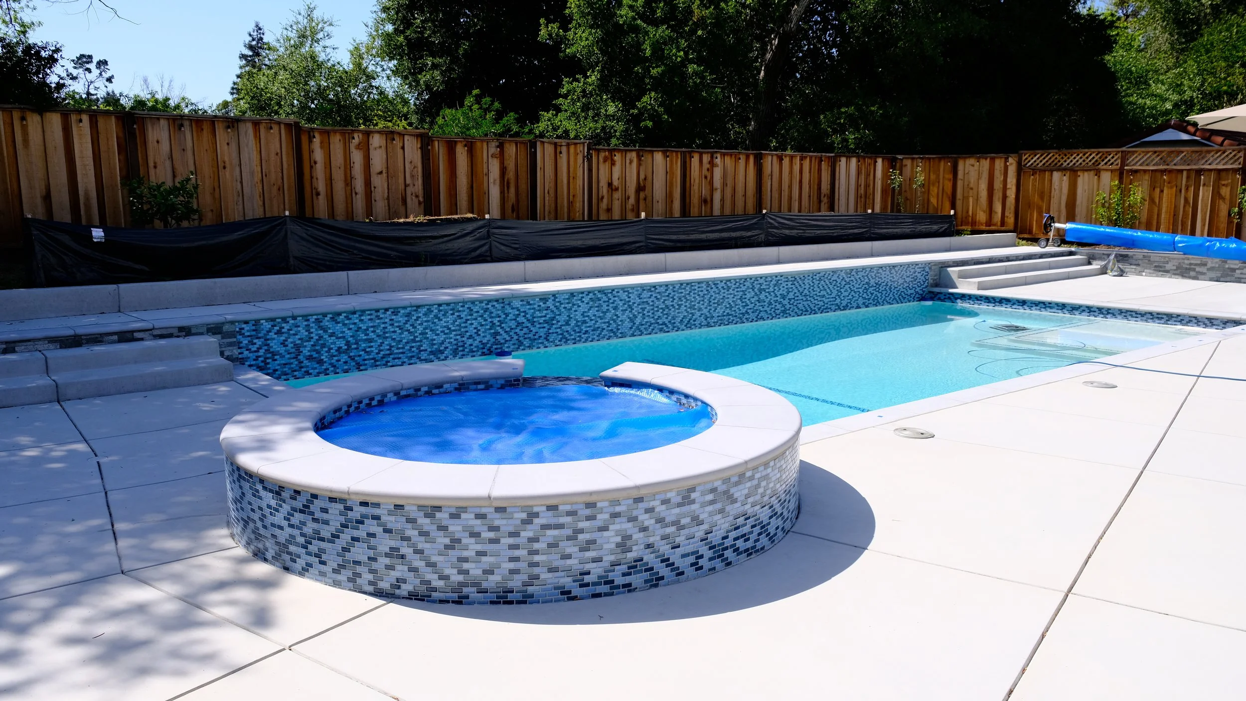 Custom gunite pool with attached spa featuring blue glass mosaic tile and modern design by NorCal Pools Inc in Northern California