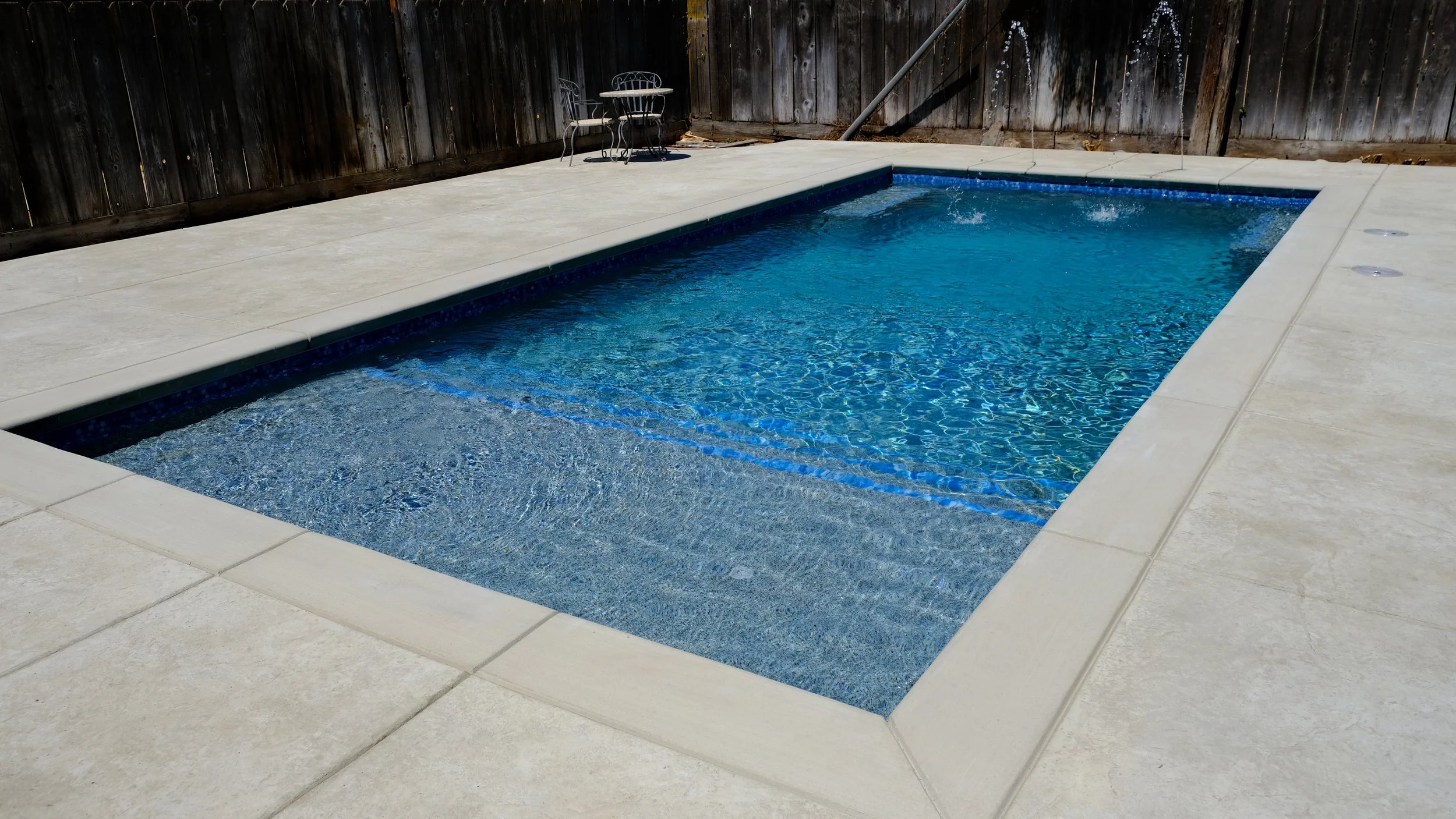 Completed pool remodel featuring blue finish and Baja shelf by NorCal Pools Inc in Northern California
