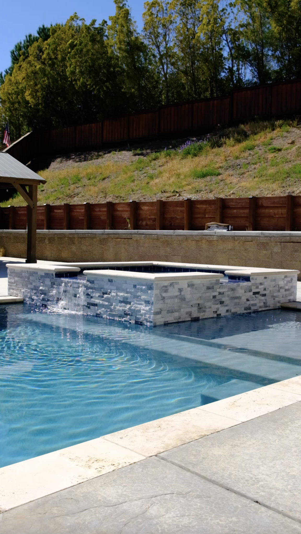 Custom pool and spa with mosaic tile and waterfall feature by NorCal Pools Inc in Northern California