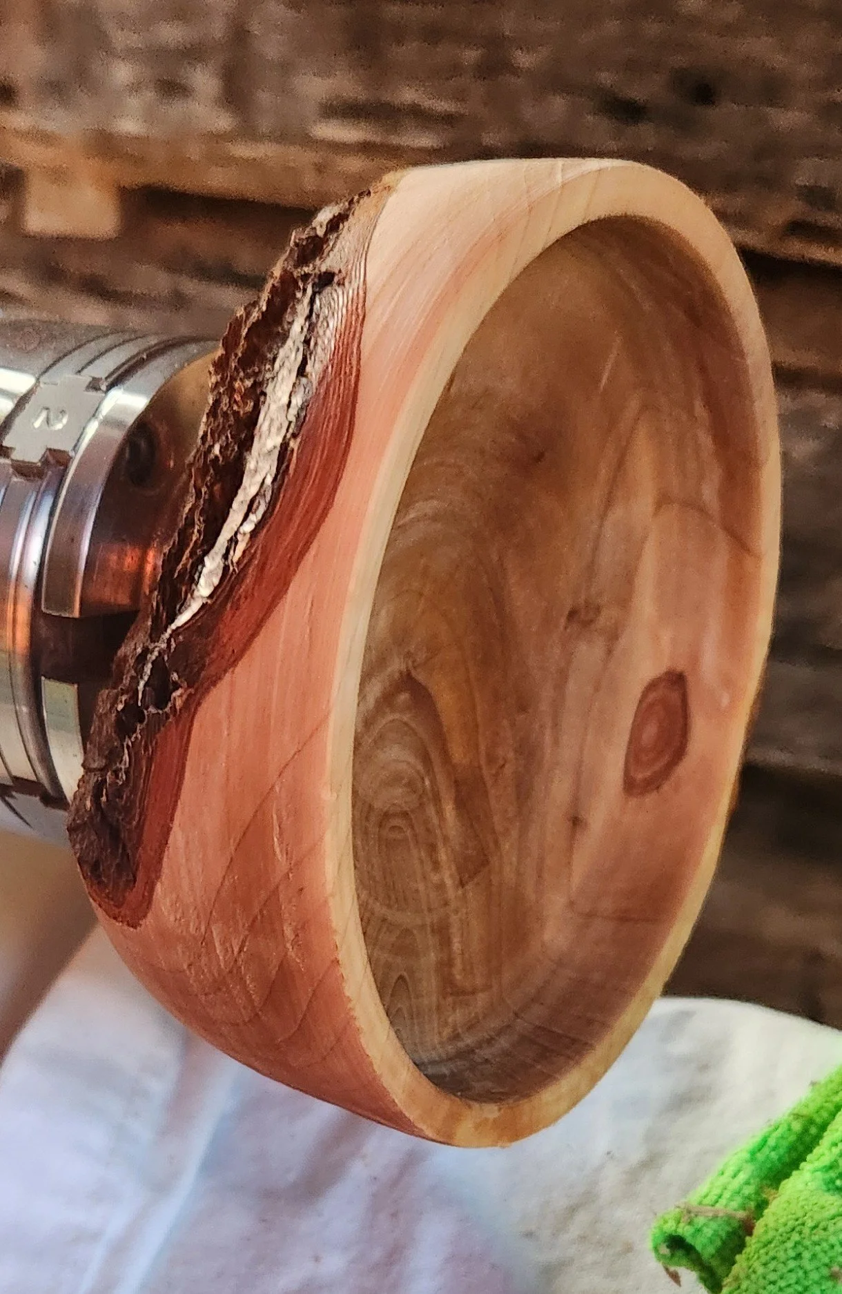 Close-up of a wooden bowl with natural bark edge mounted on a wood lathe.
