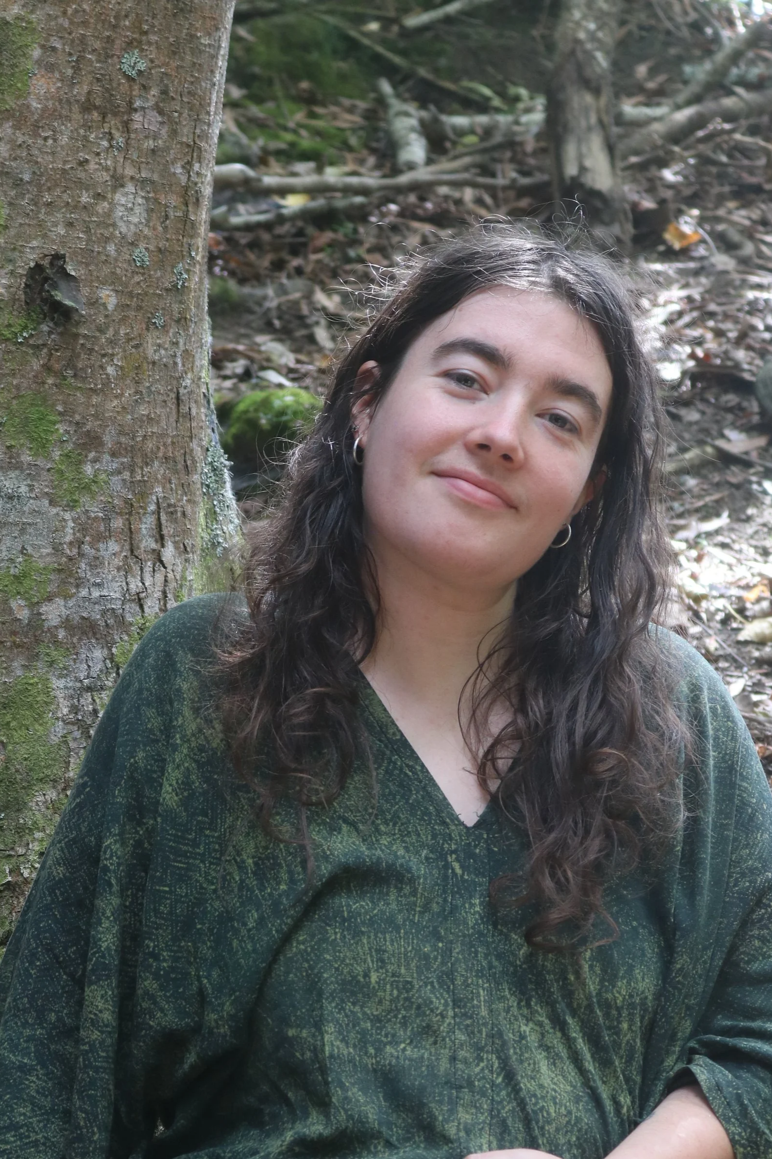 Image of naturopathic practitioner out in nature, surrounded by greenery, moss, and tree trunks