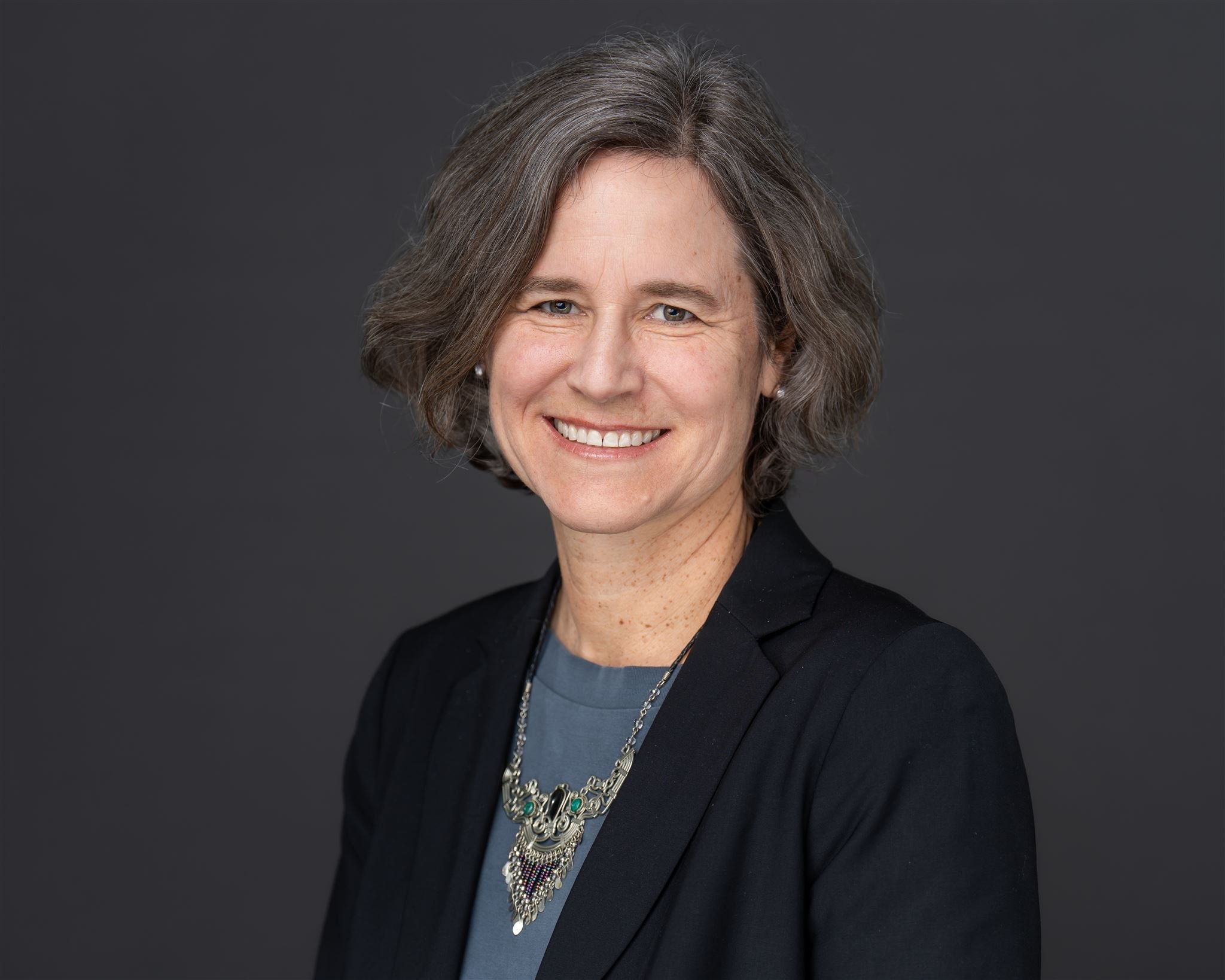 Black and white portrait of a smiling woman with long dark hair wearing a turtleneck sweater.