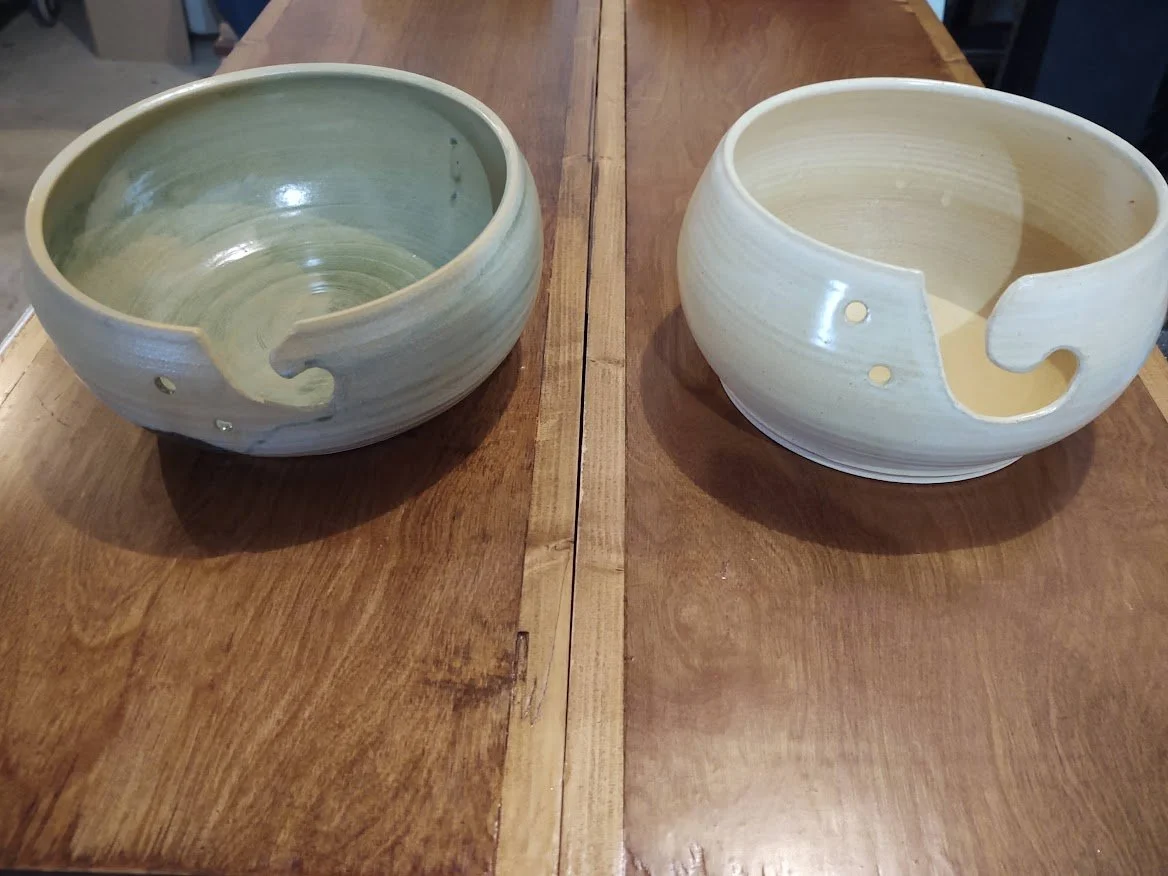 Two ceramic bowls with a swirl design on a wooden table, one greenish and one white, with the swirl opening facing outward.