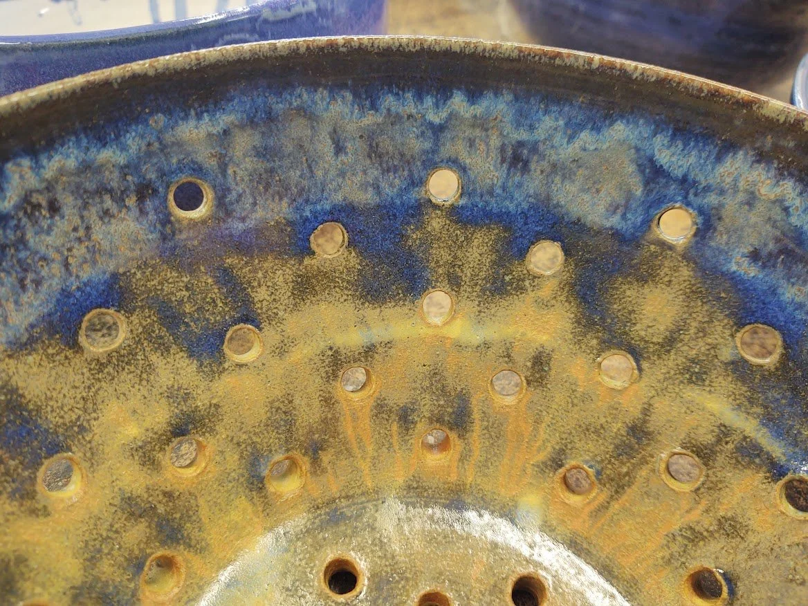 Close-up of a ceramic colander with multiple small circular holes.