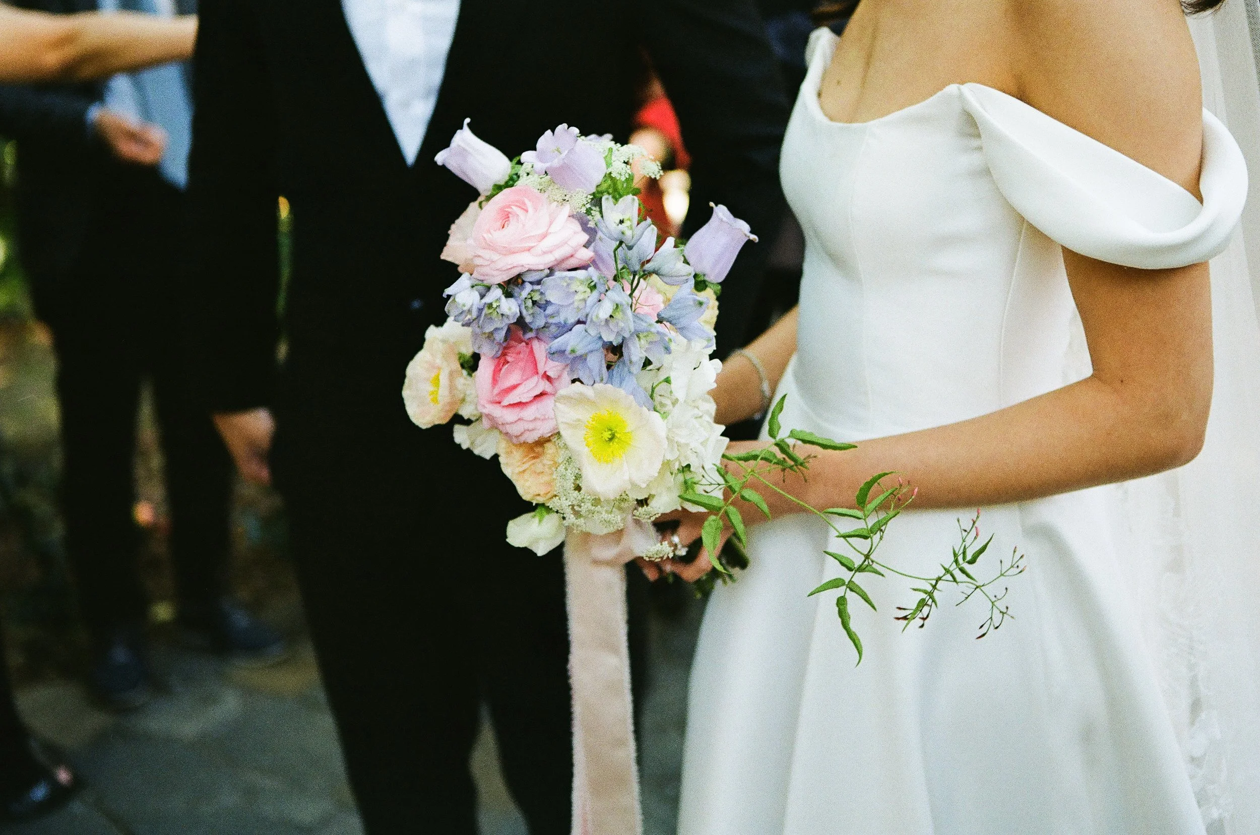 Bride holding a colorful bouquet of flowers during a wedding ceremony.