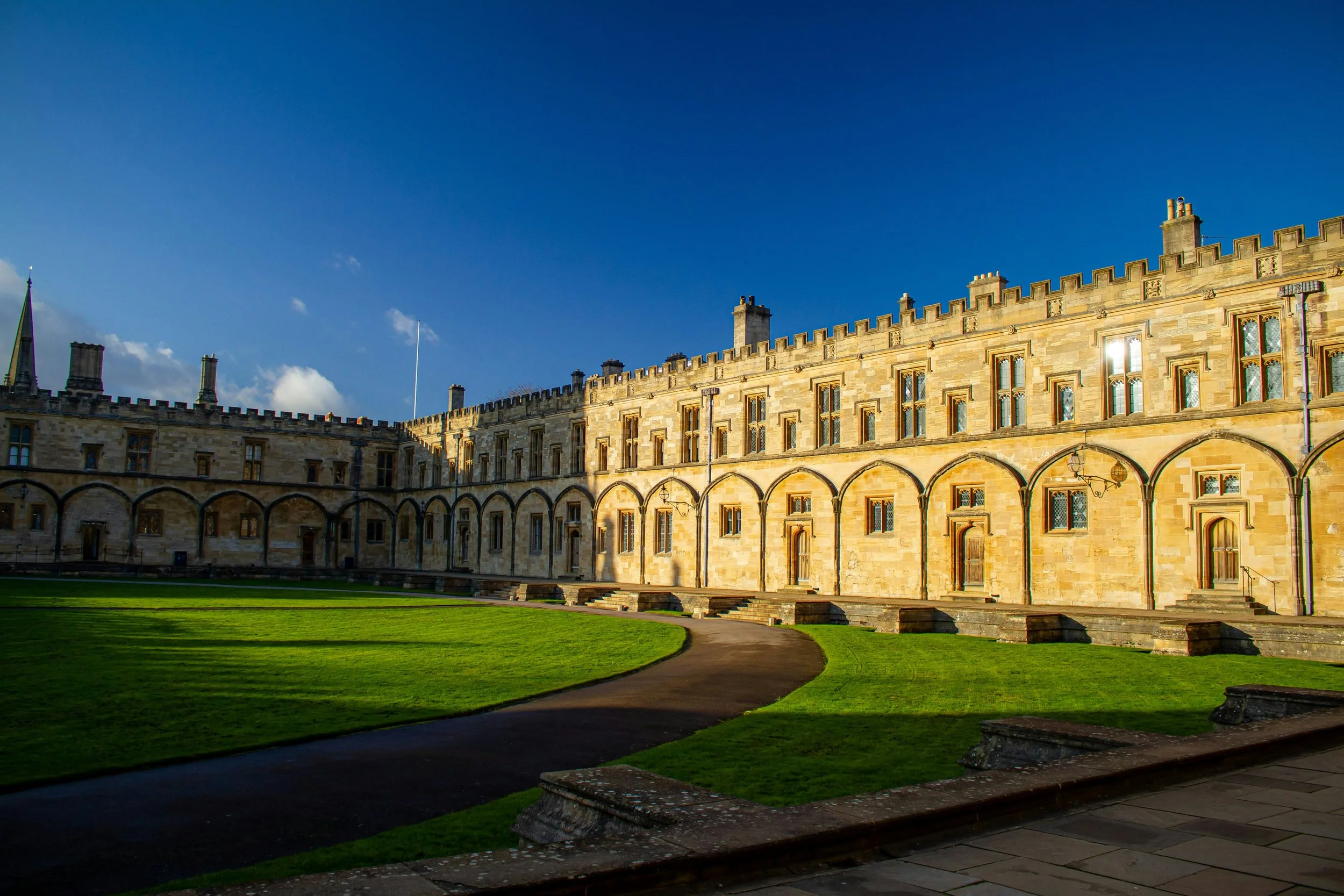 View of a historic quad at an Oxford college with a grassy courtyard and a blue sky with a few clouds.