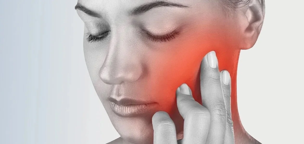 Frau mit rot markiertem Schmerzbereich an Kiefer und Wange als Symptom von CMD und Bruxismus