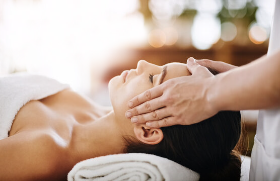 A woman receiving a massage on her face at a spa or wellness center