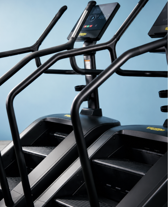 Close-up of two black treadmills with digital screens and control panels against a blue background.
