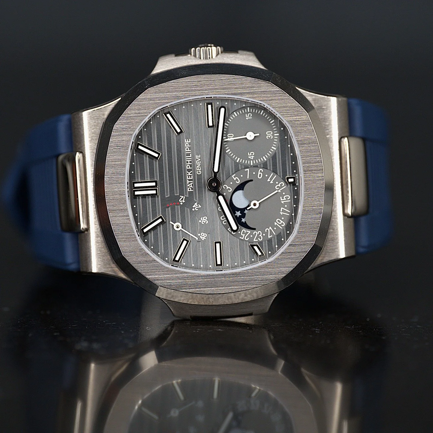 Patek Philippe Geneva wristwatch with a gray face, blue strap, moon phase, and multiple dials against a black background.