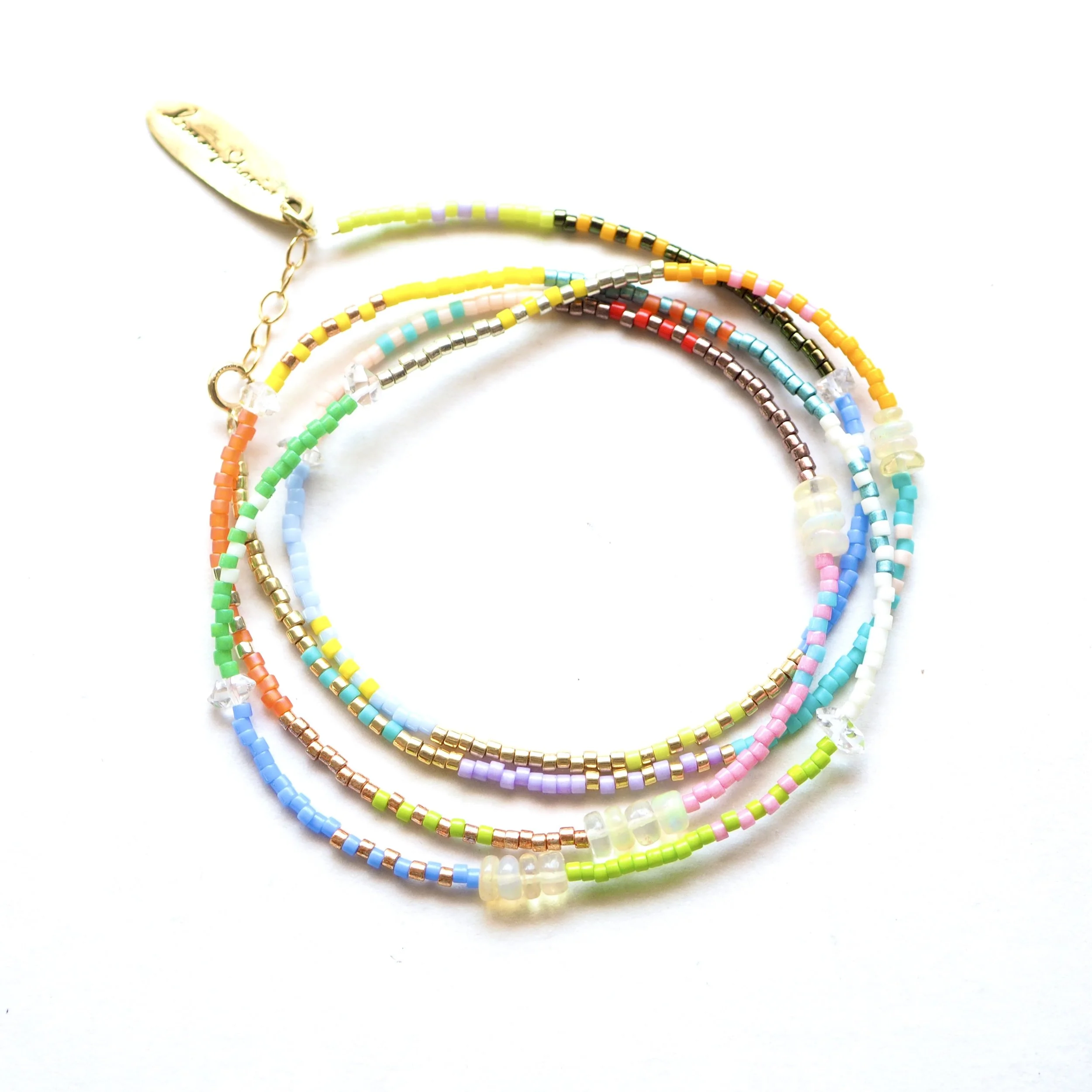 Colorful beaded bracelet with a small shell charm on a white background.