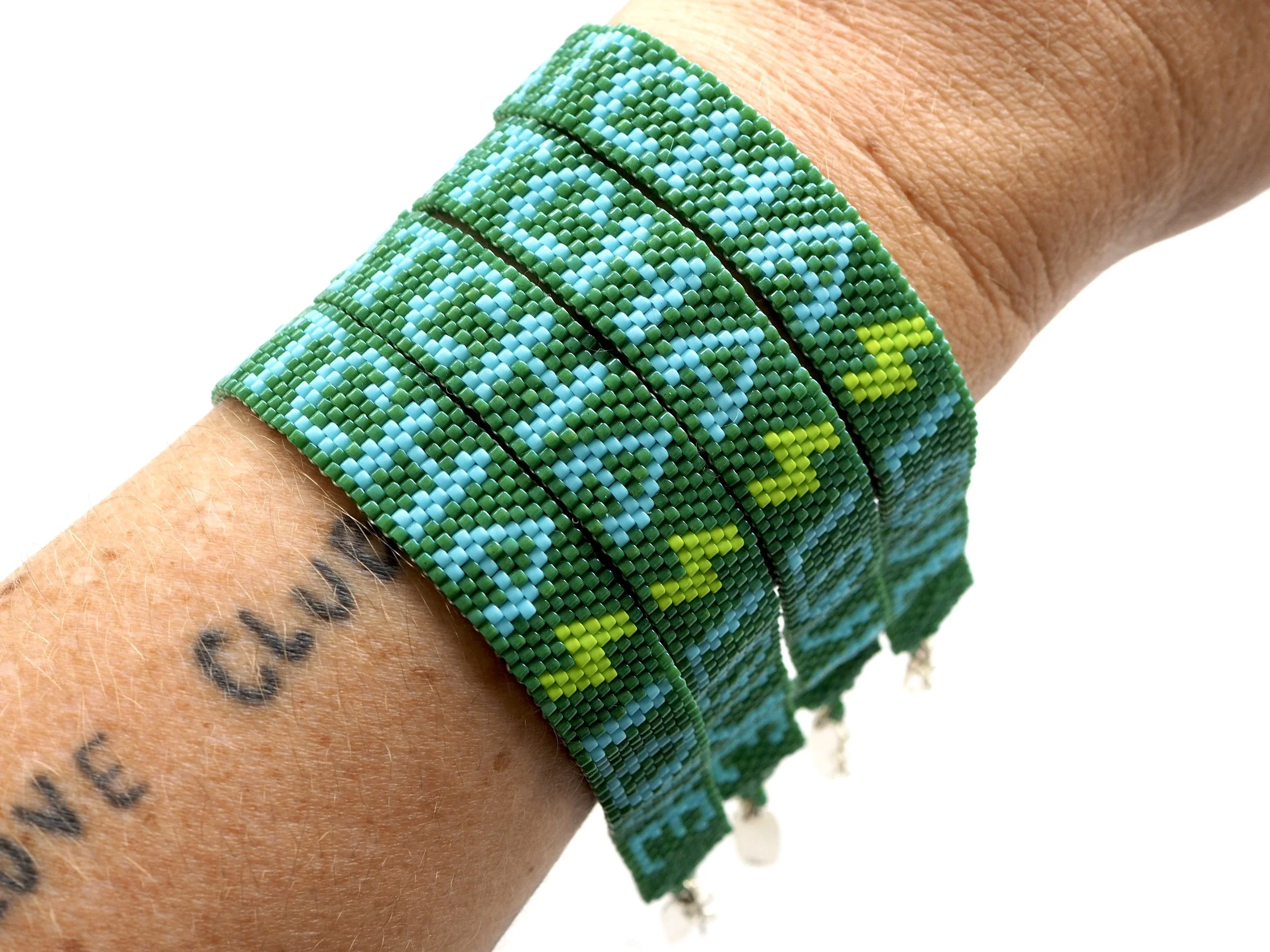 Colorful beaded Bunny Shapiro bracelets for Jenki Matcha on a person's wrist with a tattooed arm.