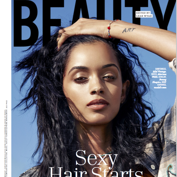 A young woman with long, curly black hair, wearing a plaid shirt, poses with her hand on her head against a blue sky background on the cover of a magazine wearing a Bunny Shapiro bracelet.  This ad is from Cosmopolitan Magazine.