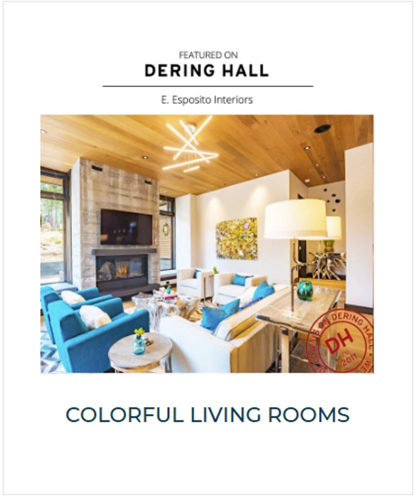 Interior of a colorful living room featuring a stone fireplace, multiple white sofas with blue and turquoise pillows, and a wooden ceiling with modern light fixtures.