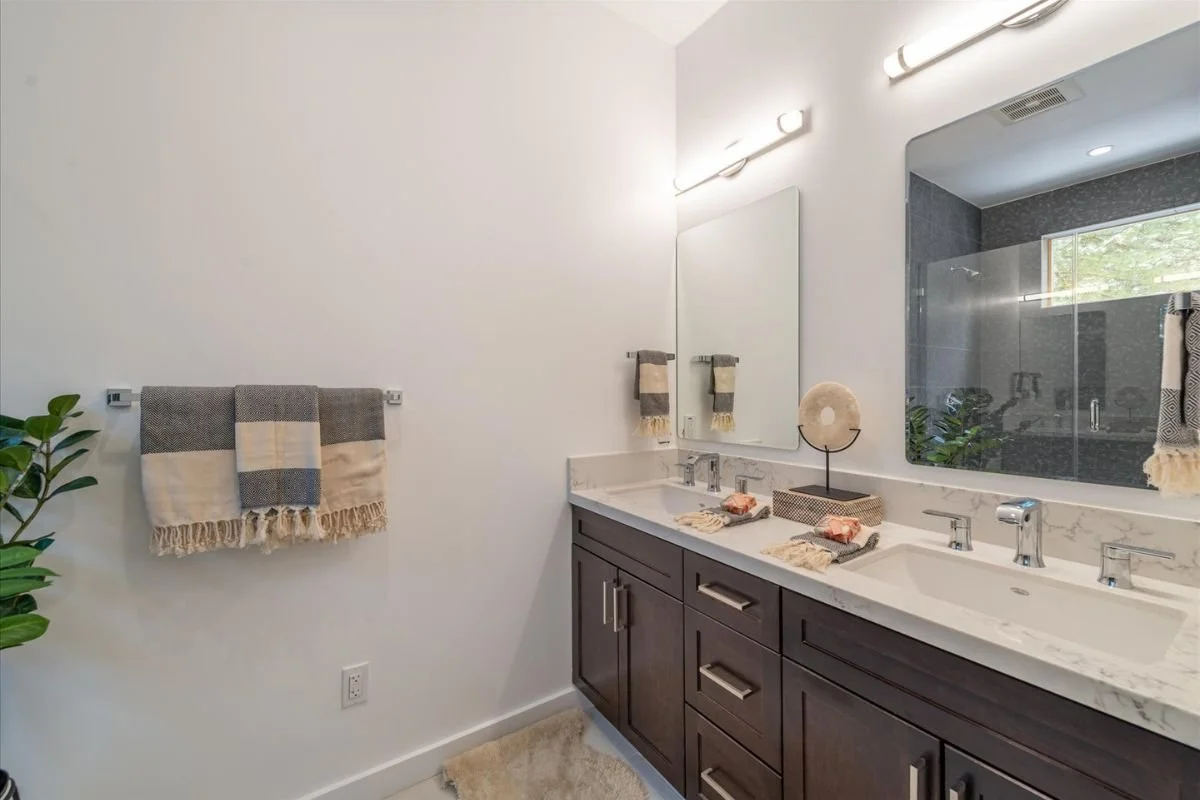 Modern bathroom with double vanity, large mirror, and decorative items on counter.
