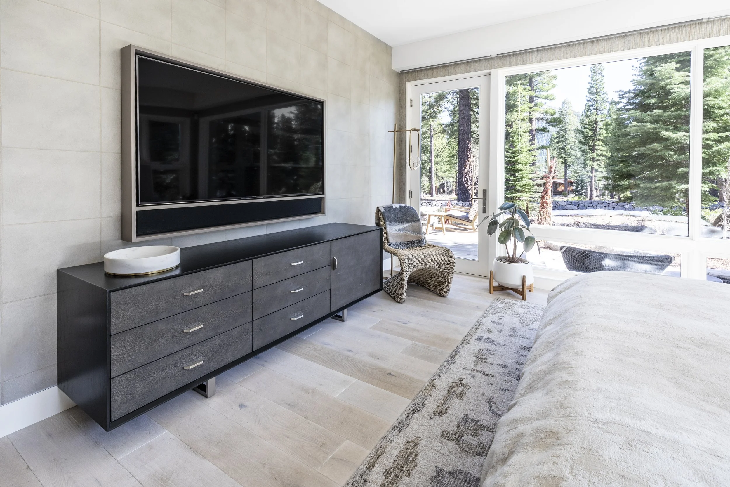 Primary mountain modern bedroom created to be luxurious with warm woods, cream, gold, and tan accents with the walls dressed in two different wallpapers. The window shades are recessed for a more modern and sleek design. Custom wood floors and ample 