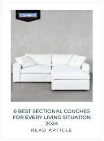 White sectional sofa in a room with a plain gray wall, an American flag and US Navy sign.