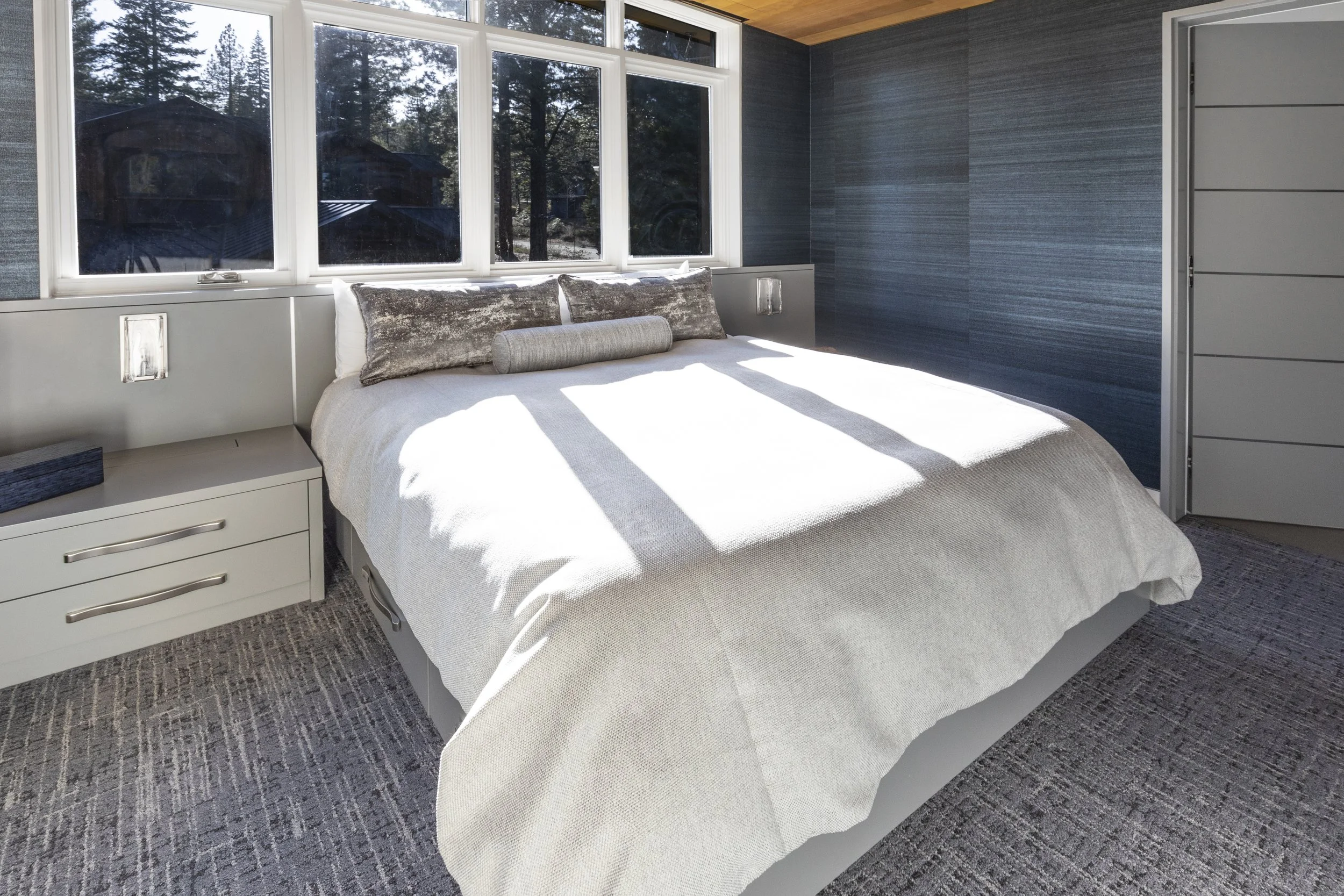 Custom designed and built-in bed, headboard, and nightstands that have hidden outlets for charging devices. Walls covered in wallpaper and the ceiling is clad in cedar T&G wood in Martis Camp in Truckee, CA.